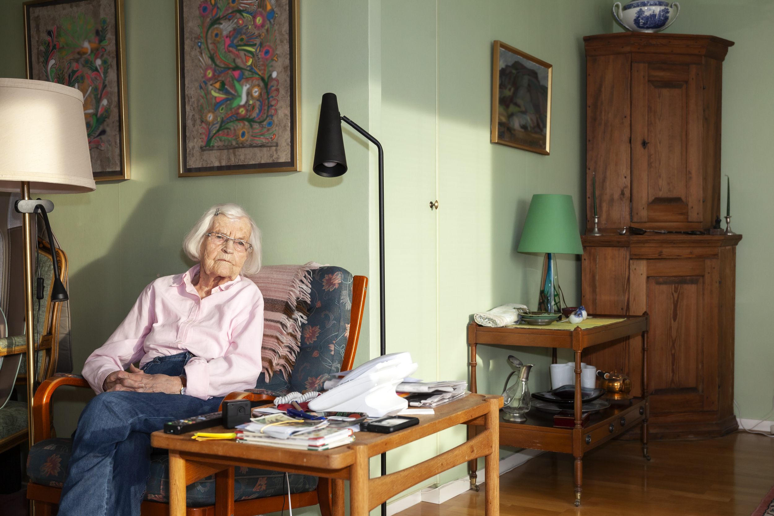 Äldre kvinna sitter i fåtölj.