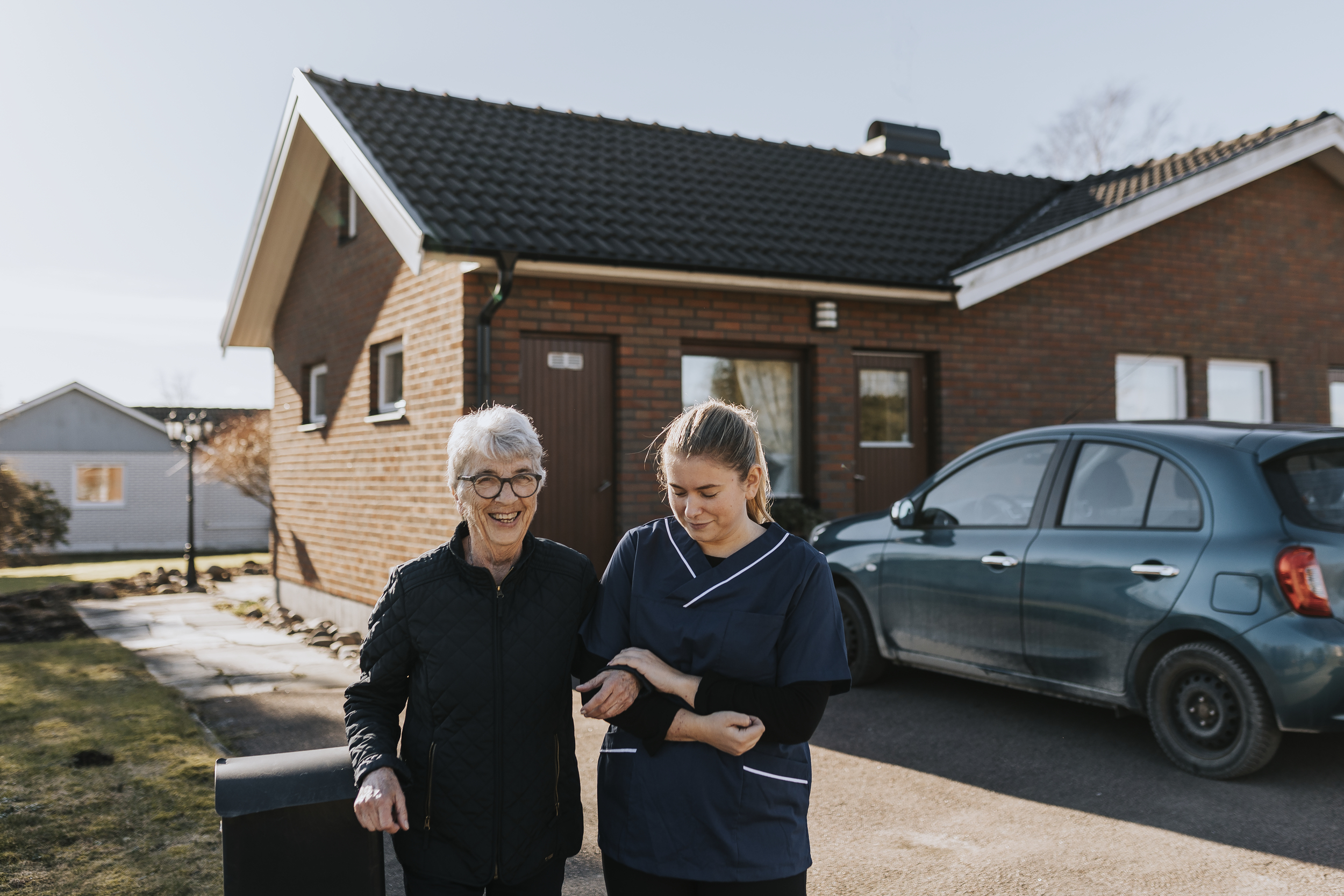 Hemtjänstpersonal går ute med äldre kvinna
