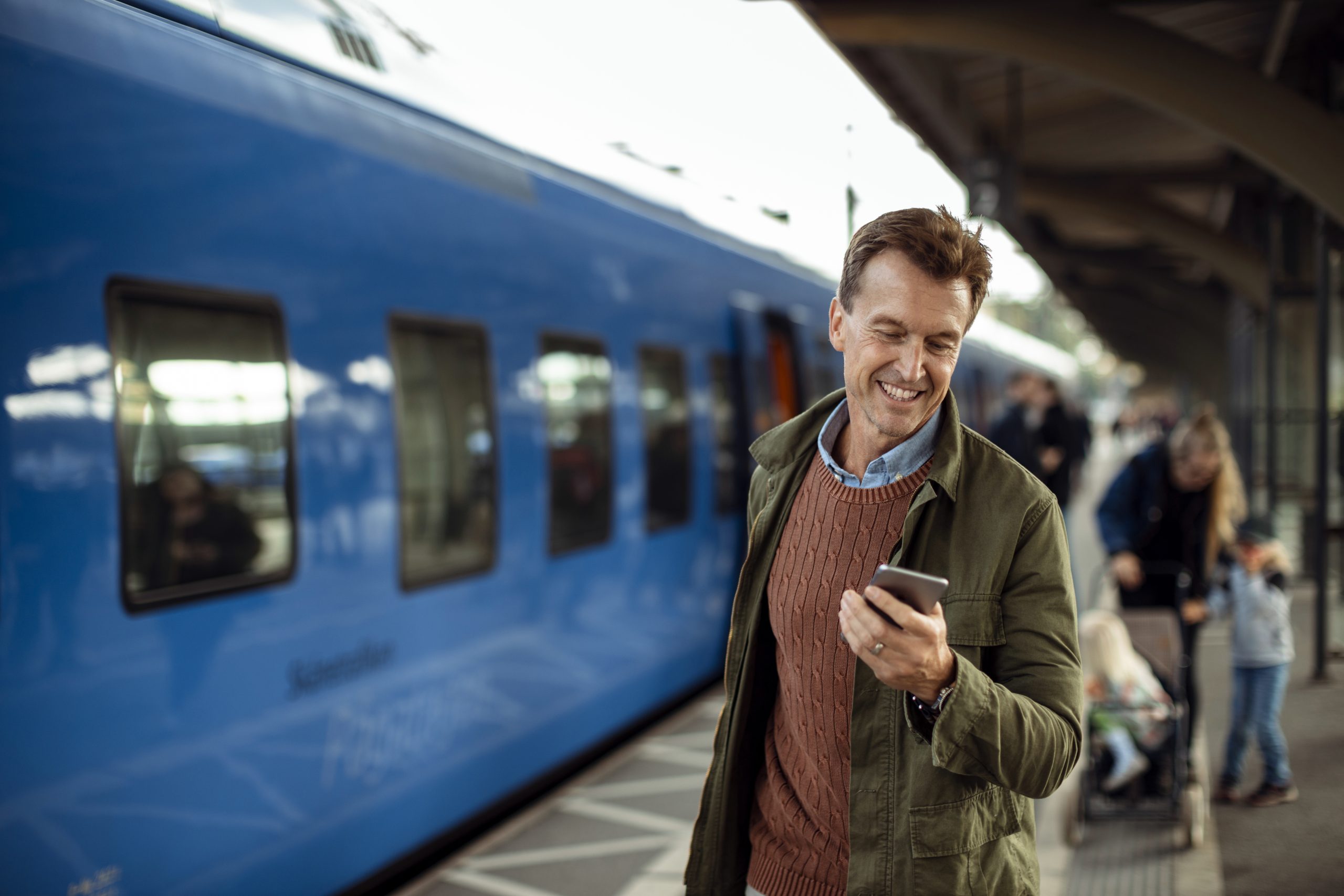Närbild på man med mobiltelefon på en tågstation